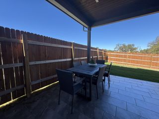 A cozy patio with a sleek outdoor table set, fenced yard, and a paved tile floor, perfect for relaxation.