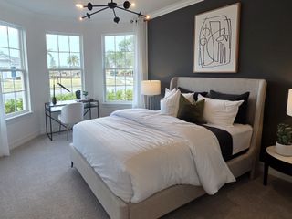 A cozy bedroom with large windows, a dark accent wall, and elegant lighting for a stylish and relaxing retreat.
