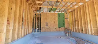 Under-construction interior with exposed framing, insulation, and wiring, ready for further development and finishing.