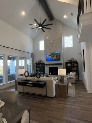 A bright, open living space features soaring ceilings, a modern fireplace with a marble surround, and stylish contemporary furnishings.