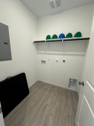 A functional laundry room with sleek shelving and wood-look flooring, perfect for organizing household essentials.