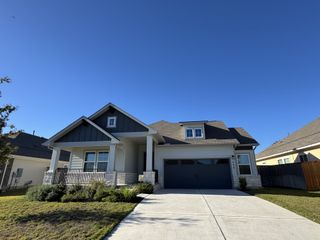 A modern home with dark accents and a manicured lawn in Cypress Forest by Scott Felder Homes (Kyle, TX).