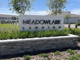 A beautifully landscaped entrance to Meadowlark Landing by Mattamy Homes in Apopka, FL, with elegant signage and greenery.