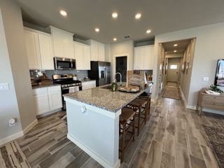 Model Home A contemporary kitchen featuring white cabinetry, granite countertops, and stainless steel appliances. A central island with barstool seating offers additional workspace and dining space.