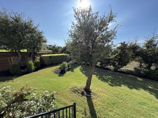 A beautifully landscaped backyard featuring a lush green lawn, mature trees, and well-maintained flower beds, offering a serene outdoor space.