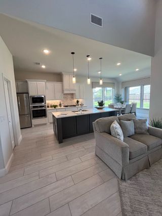 A spacious open-plan kitchen and living area with modern lighting, sleek cabinetry, and cozy seating.