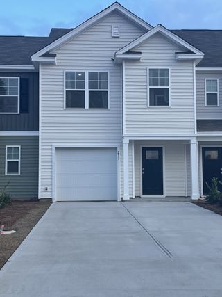 Street view A modern white townhome with a neat facade in Pine Hills Townhomes at Cane Bay by D.R. Horton (Summerville, SC).