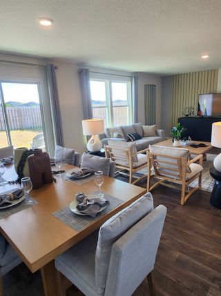 An open-concept dining and living area with large windows, modern furnishings, and warm tones in Copes Landing by D.R. Horton (Jacksonville, FL).