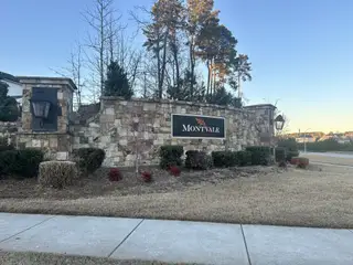 Street view Elegant stone entrance with lush landscaping at Montvale at Copperleaf by Upright Builders in Cary, NC.