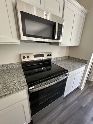 A modern kitchen with sleek stainless steel appliances, granite countertops, and elegant white cabinetry.