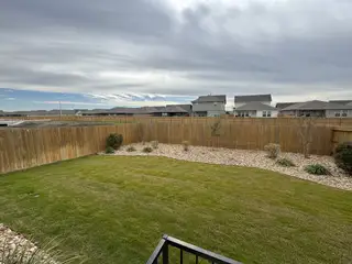 A spacious backyard with lush green grass, a privacy fence, and decorative landscaping, ideal for outdoor activities and gatherings.