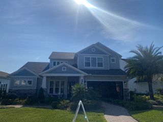 A beautiful blue home with stone accents and lush landscaping in Middlebourne by ICI Homes (St. Johns, FL).