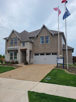 A charming brick home with a well-kept lawn and flag display in Legacy Ranch Classic 60 by Bloomfield Homes (Melissa, TX).