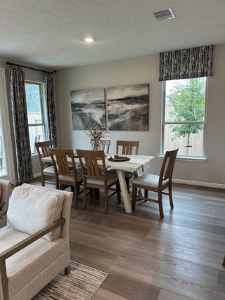 A cozy dining room with wooden floors, neutral-toned furniture, and abstract wall art.