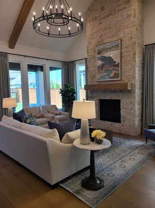 A cozy living room with a stone fireplace, elegant chandelier, and plush seating, creating a warm and inviting atmosphere.