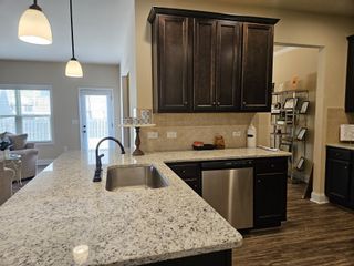 A modern kitchen featuring granite countertops, dark wood cabinets, and sleek stainless steel appliances.