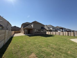 Model Home A two-story brick home with a covered patio and lush green lawn in Bluffview by Pulte Homes (Leander, TX).
