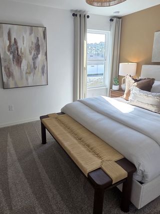 A cozy bedroom with warm tones, textured bench, abstract art, and ample natural light.