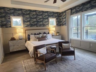 A cozy bedroom featuring a patterned accent wall, large windows, and elegant furnishings.