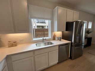 A sleek kitchen with white cabinetry, stainless steel appliances, and under-cabinet lighting.