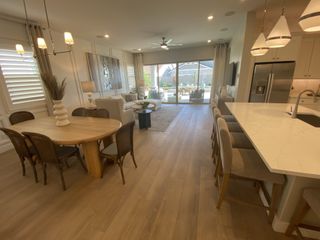 An elegant open-plan living space with wood flooring, modern lighting, and a spacious kitchen island.