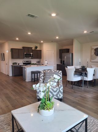 Model Home Open-concept living space with modern kitchen, wood floors, and elegant dining area under soft lighting.
