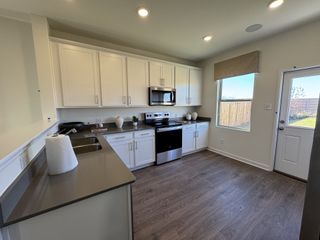 Contemporary kitchen with white cabinets, stainless steel appliances, and a sleek black countertop.