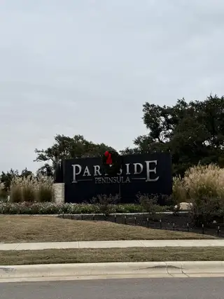 A welcoming entrance with lush landscaping at Parkside Peninsula 50' by Perry Homes in Georgetown, TX.