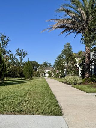 Community Amenities Charming pathway with lush greenery and palm trees in Kindlewood Forest by D.R. Horton in Middleburg, FL.