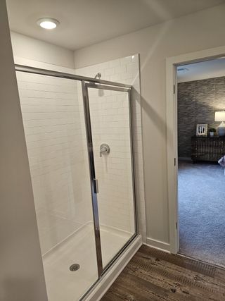 Model Home A modern walk-in shower with sleek glass doors, white subway tiles, and a spacious layout.