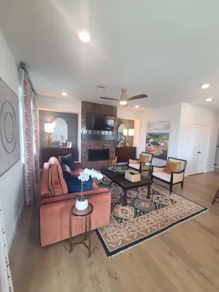 Model Home A cozy living room featuring a rustic brick fireplace, elegant rug, and plush seating.