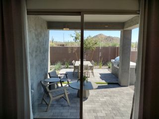 Cozy patio with outdoor seating, a dining table, and a serene view of desert landscaping under a covered area.