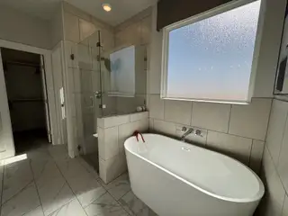 A modern bathroom featuring a sleek freestanding tub, glass-enclosed shower, and elegant tile flooring.