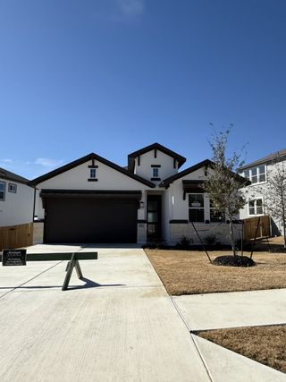 Street view A modern home with a spacious driveway and neat landscaping in Lakeside at Tessera on Lake Travis by Saratoga Homes (Lago Vista, TX).