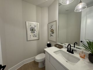 A modern bathroom with elegant wall art, sleek white vanity, black fixtures, and stylish lighting.