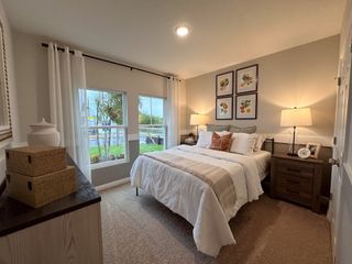 A cozy bedroom with a plush carpet, elegant bedding, warm lighting, and botanical wall art.