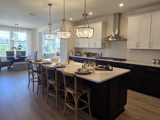 Model Home A modern kitchen with a large island, elegant pendant lights, and seating area in an open-plan design.