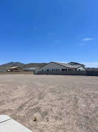 Street view Expansive desert lot with a modern home at Laveen Vistas II by Homes by Towne, set against scenic Phoenix, AZ mountains.