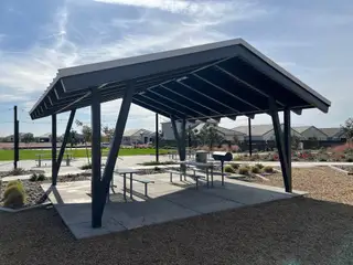 A modern pavilion with picnic tables and barbecue area in Radiance At Superstition Vistas by D.R. Horton (Apache Junction, AZ).