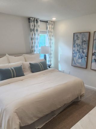 Model Home A cozy bedroom with a plush bed, patterned curtains, and abstract art, creating a serene and inviting atmosphere.