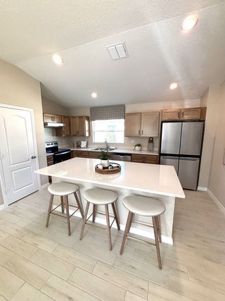 A modern kitchen with light wood cabinets, a central island, and sleek stainless steel appliances.
