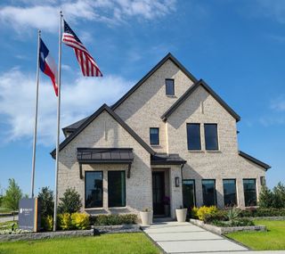 A beautiful beige brick home with a manicured lawn in Painted Tree - Woodland West by Normandy Homes (McKinney, TX).