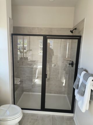 A modern bathroom with a sleek glass shower, tiled walls, and elegant towel rack.