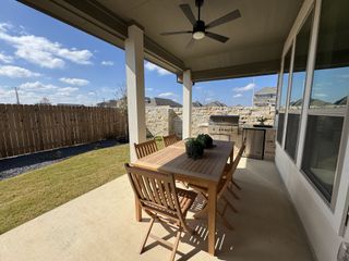 Model Home A charming patio featuring a wooden dining set, ceiling fan, and built-in grill, perfect for outdoor entertaining.