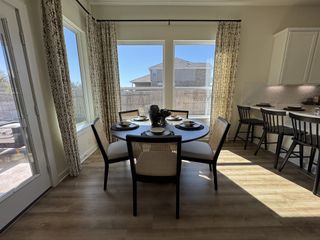 A bright dining area with a round table, elegant chairs, and large windows, complemented by modern bar seating.