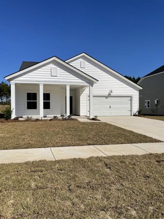 A charming white home with a spacious front porch in Heron's Walk at Summers Corner: Row Collection by Lennar (Ridgeville, SC).