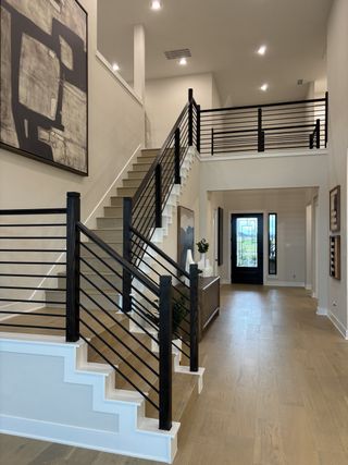 A modern entryway with sleek railings, abstract artwork, and light wood flooring.