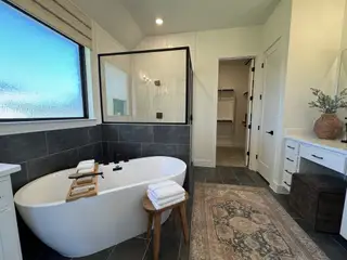 A luxurious bathroom featuring a freestanding tub, slate tiles, and a cozy rug with contemporary accents.