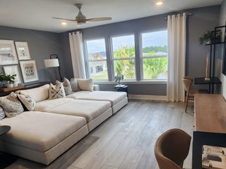 A stylish loft or entertainment space featuring a sectional sofa, large windows with natural views, and a built-in work desk.