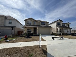 Street view A modern stone-accented home with a neat driveway in Meyer Ranch by Princeton Classic Homes (New Braunfels, TX).